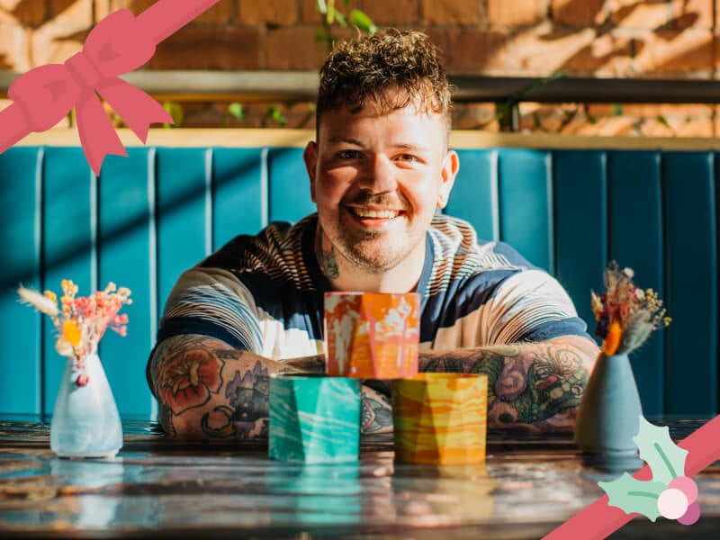A man smiles at a table with resin plant pots 